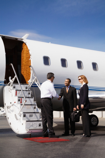 Pilot Greeting Businesspeople Boarding Executive Jet